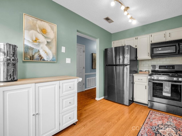 kitchen featuring backsplash, visible vents, white cabinets, and stainless steel appliances