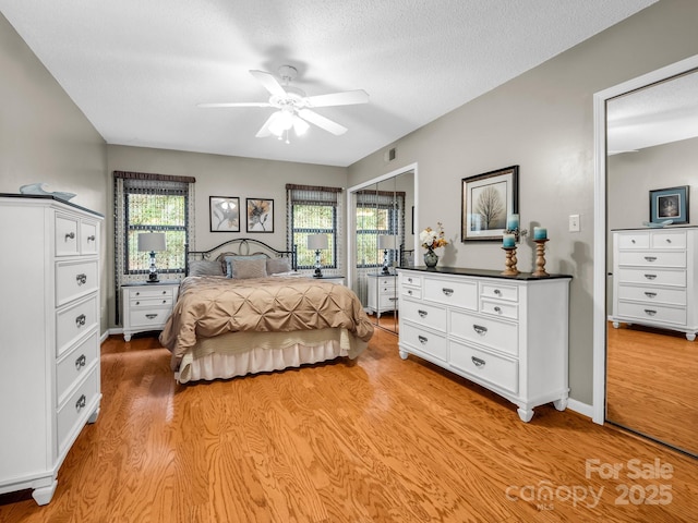 bedroom featuring a ceiling fan, visible vents, light wood finished floors, and a textured ceiling