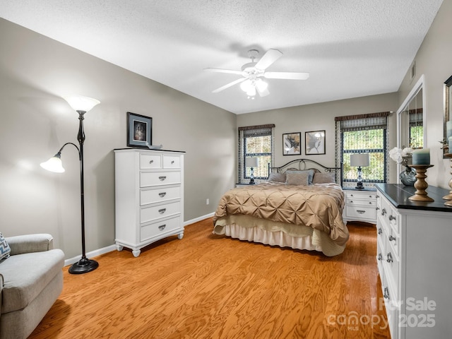 bedroom featuring multiple windows, a textured ceiling, light wood-style floors, and ceiling fan