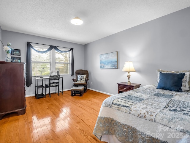 bedroom featuring a textured ceiling, light wood-type flooring, and baseboards