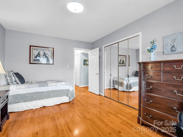 bedroom with light wood-style flooring, baseboards, and a closet