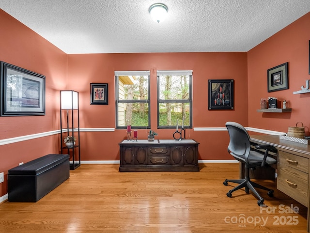 home office featuring baseboards, a textured ceiling, and light wood-style floors