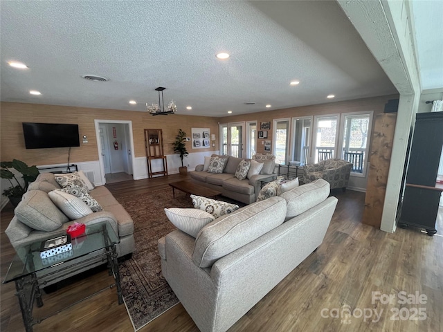 living room with recessed lighting, a textured ceiling, an inviting chandelier, and wood finished floors