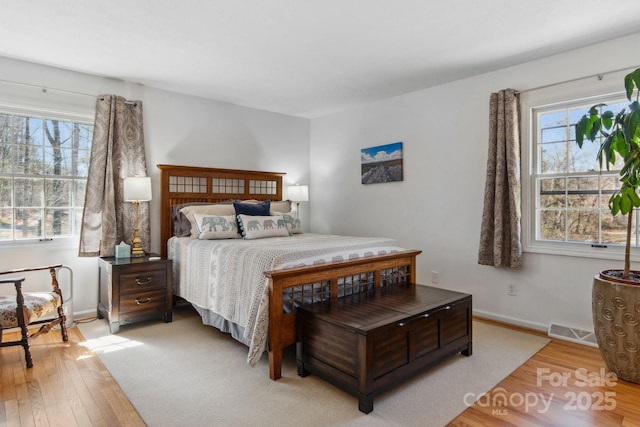 bedroom with light wood-style flooring, visible vents, and baseboards