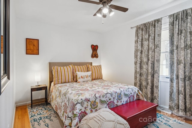 bedroom with ceiling fan, baseboards, and wood finished floors