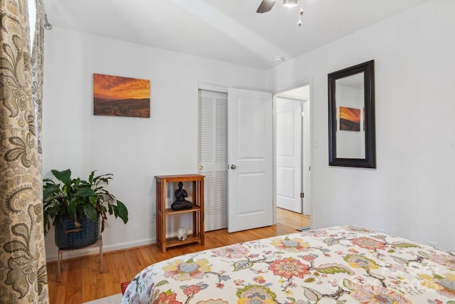 bedroom with light wood finished floors, a closet, a ceiling fan, and baseboards