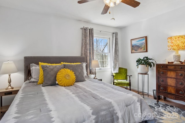 bedroom with ceiling fan, wood finished floors, and baseboards