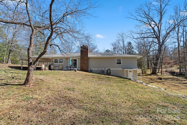 view of front of home featuring a patio, a front lawn, a chimney, and an attached carport