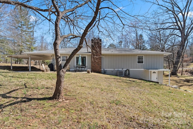 back of property featuring central AC unit, a yard, crawl space, a carport, and a chimney