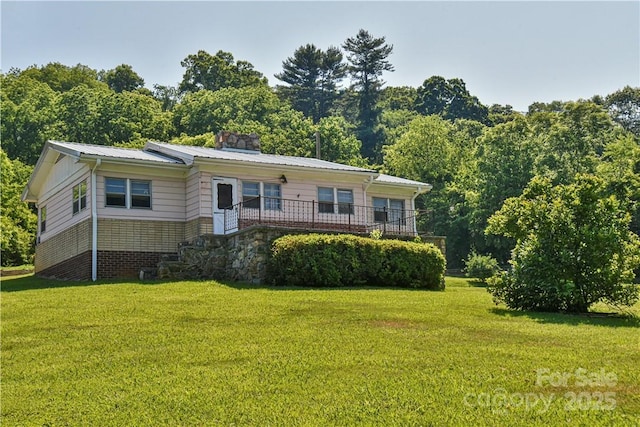view of front of home featuring metal roof and a front lawn