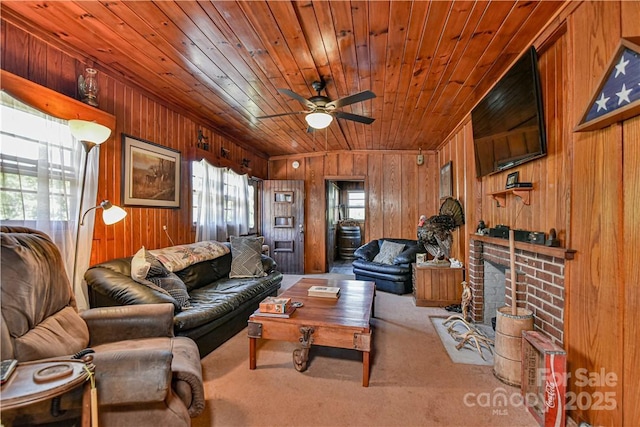 living room with ceiling fan, wood walls, wood ceiling, and carpet