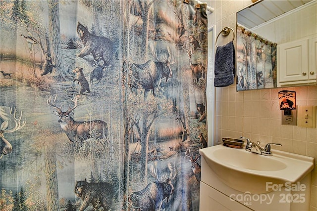 bathroom with tasteful backsplash, crown molding, tile walls, and vanity