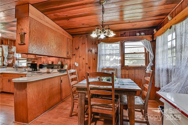 dining area featuring a chandelier, wood walls, wood ceiling, and light wood-type flooring