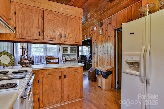kitchen with wood walls, wood ceiling, light wood-type flooring, light countertops, and white appliances