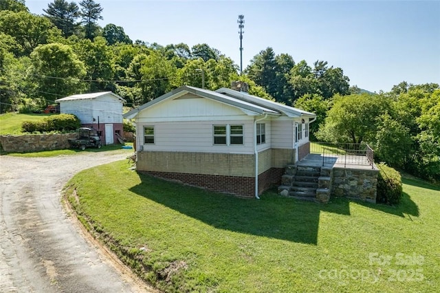 view of side of home with a lawn, board and batten siding, and driveway