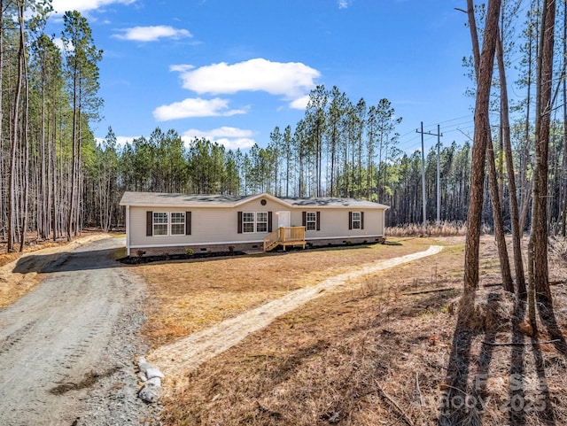 manufactured / mobile home featuring driveway, crawl space, and a view of trees