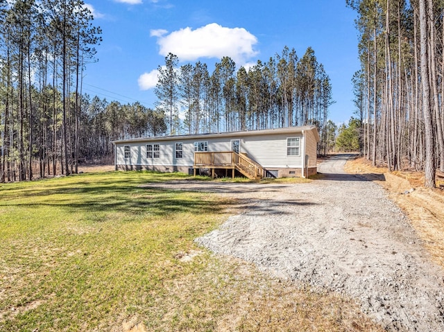 manufactured / mobile home with crawl space, driveway, a wooden deck, and a front lawn