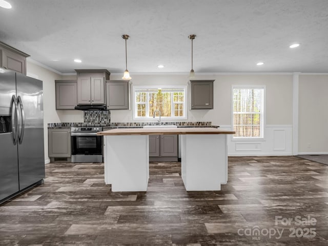 kitchen with appliances with stainless steel finishes, a center island, a sink, and gray cabinetry