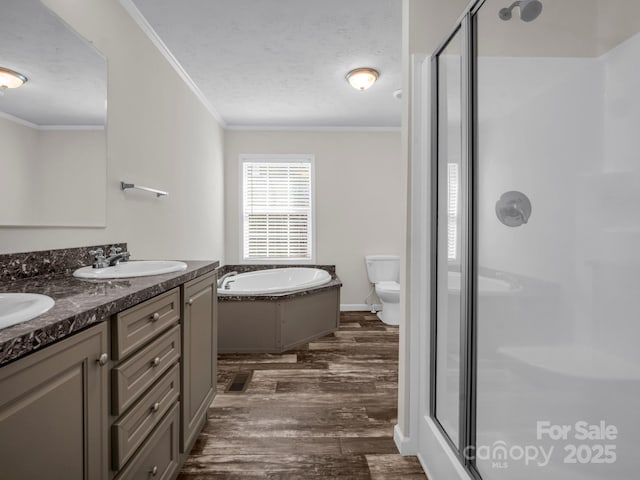 bathroom featuring wood finished floors, a stall shower, a sink, and crown molding