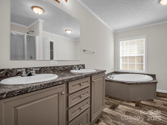 full bathroom with ornamental molding, a sink, a shower stall, and wood finished floors