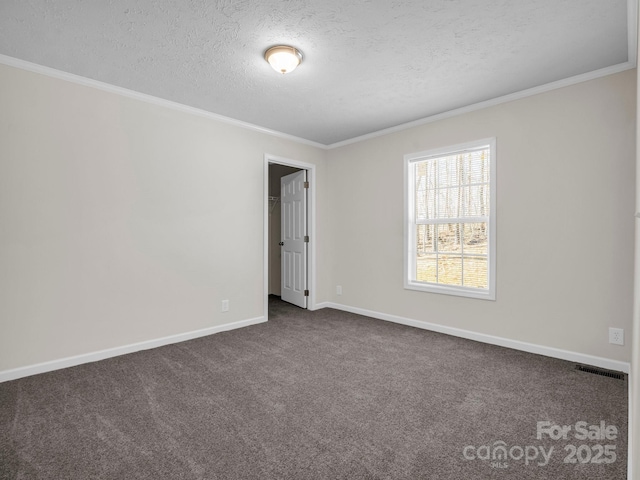 empty room with baseboards, visible vents, ornamental molding, dark colored carpet, and a textured ceiling