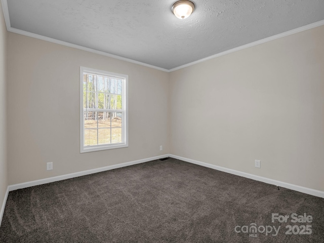 spare room with a textured ceiling, ornamental molding, dark carpet, and baseboards