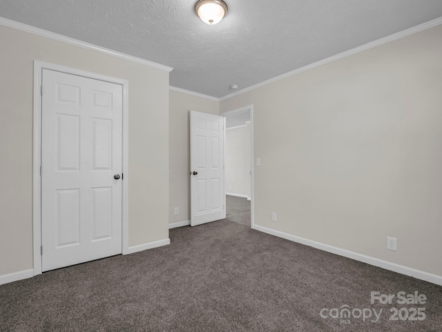 unfurnished bedroom featuring a textured ceiling, dark colored carpet, ornamental molding, and baseboards