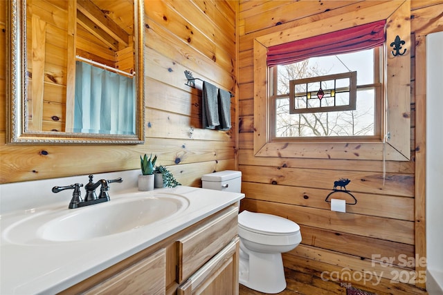 full bathroom with toilet, vanity, a shower with shower curtain, and wooden walls