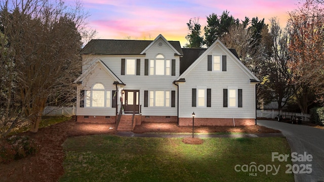 traditional home featuring a yard, crawl space, and fence