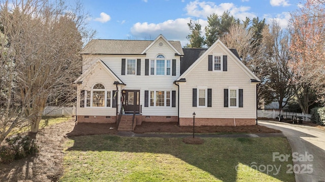 traditional home with crawl space, a shingled roof, fence, and a front lawn