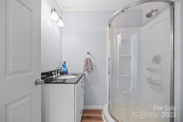 full bath featuring ornamental molding, wood finished floors, a shower stall, baseboards, and vanity