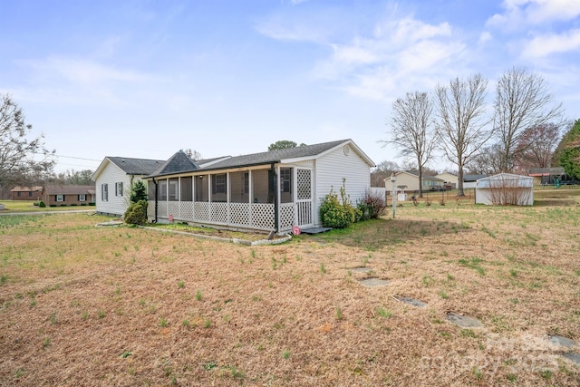 rear view of house with fence, a shed, a yard, an outdoor structure, and a sunroom