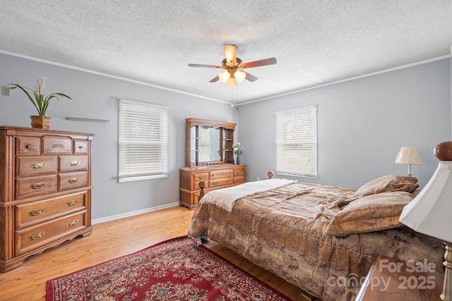 bedroom featuring baseboards, light wood finished floors, ceiling fan, a textured ceiling, and crown molding