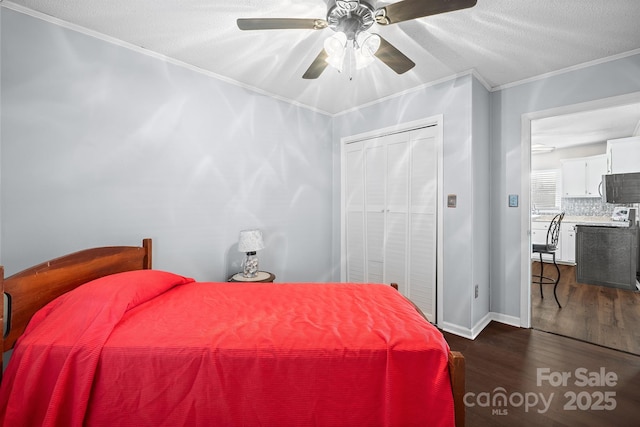 bedroom featuring a ceiling fan, dark wood-style floors, ornamental molding, a closet, and a textured ceiling