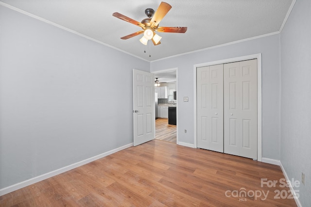 unfurnished bedroom featuring a closet, baseboards, light wood-style floors, and crown molding