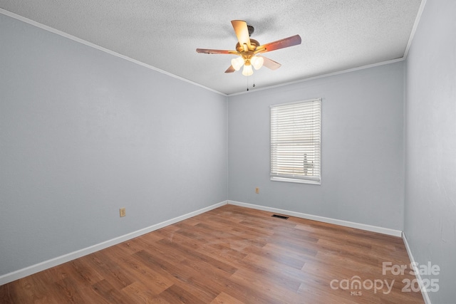 empty room featuring baseboards, ornamental molding, wood finished floors, a textured ceiling, and a ceiling fan