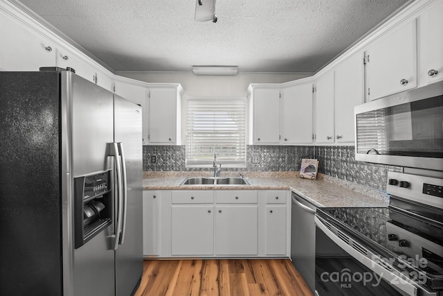 kitchen featuring white cabinetry, light wood-style floors, appliances with stainless steel finishes, and a sink