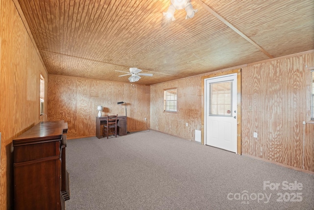 interior space with wooden walls, carpet flooring, wood ceiling, and ceiling fan