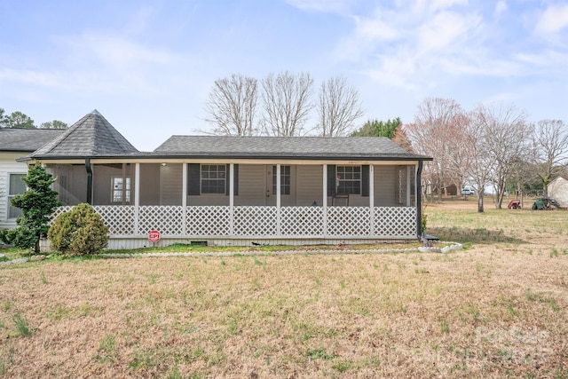 view of front of home with covered porch, a shingled roof, a front lawn, and a sunroom