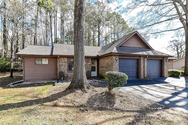 ranch-style home featuring a garage, brick siding, a shingled roof, and aphalt driveway