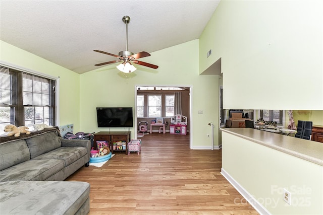 living area with visible vents, light wood-style flooring, a ceiling fan, a textured ceiling, and baseboards