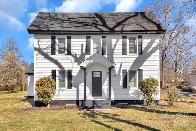 colonial home with a front lawn and roof with shingles