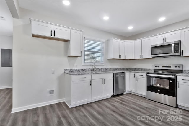 kitchen with white cabinetry, appliances with stainless steel finishes, a sink, and wood finished floors