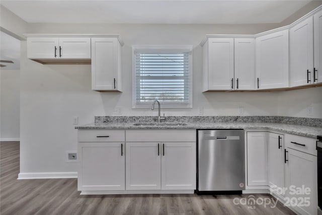 kitchen featuring wood finished floors, a sink, white cabinets, light stone countertops, and dishwasher