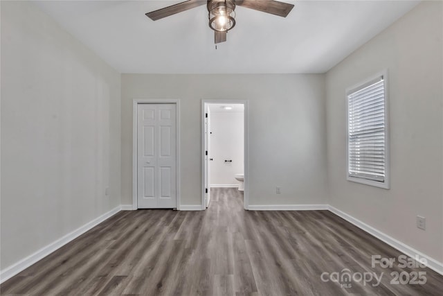 unfurnished bedroom with a closet, ensuite bathroom, baseboards, and wood finished floors