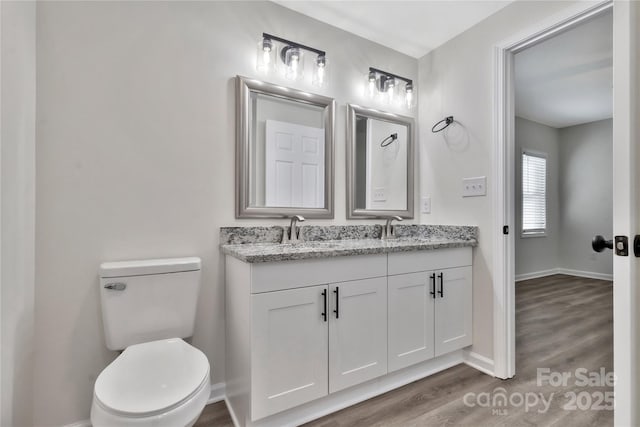 bathroom featuring wood finished floors, a sink, toilet, and baseboards