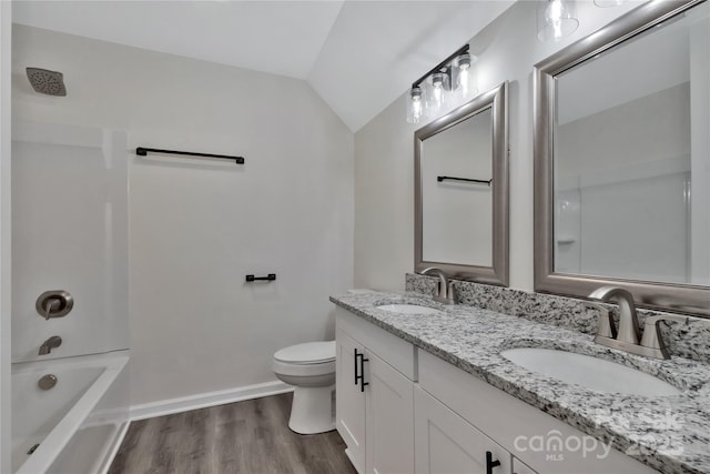 full bathroom featuring toilet, vaulted ceiling, a sink, and wood finished floors