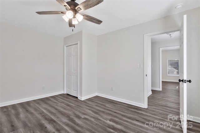 unfurnished bedroom with ceiling fan, baseboards, and dark wood-type flooring