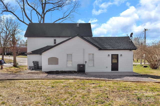 rear view of property featuring a yard, cooling unit, a patio, and a shingled roof