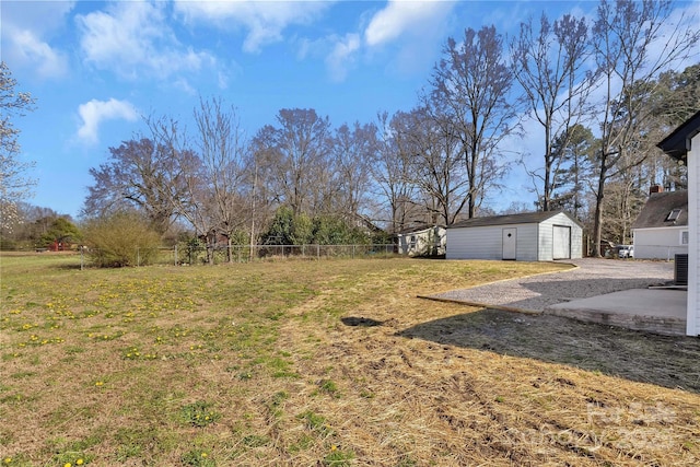 view of yard featuring a garage, central AC, an outdoor structure, and fence